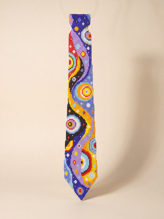 Handmade beaded tie with vibrant blue, purple and orange cosmic swirl galaxy-inspired pattern.