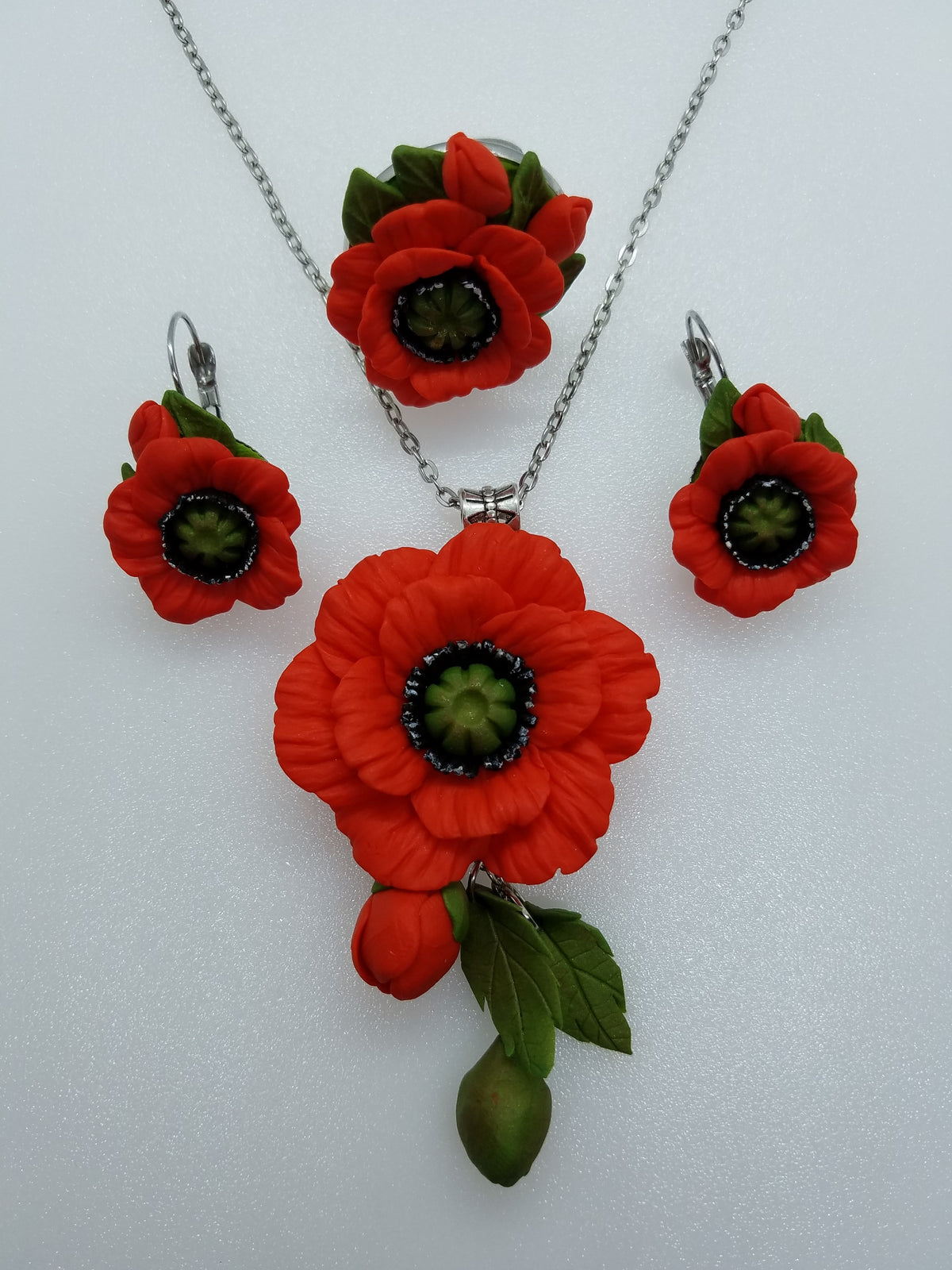 Red poppy pendant necklace shown with matching polymer clay earrings and ring from the Poppies line