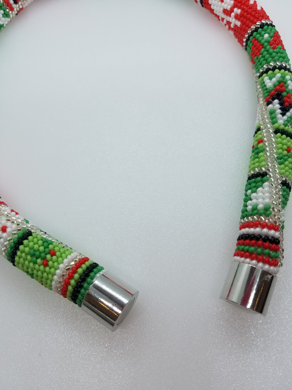 Close-up of winter folk beadwork and magnetic silver end caps on the Christmas ornaments necklace