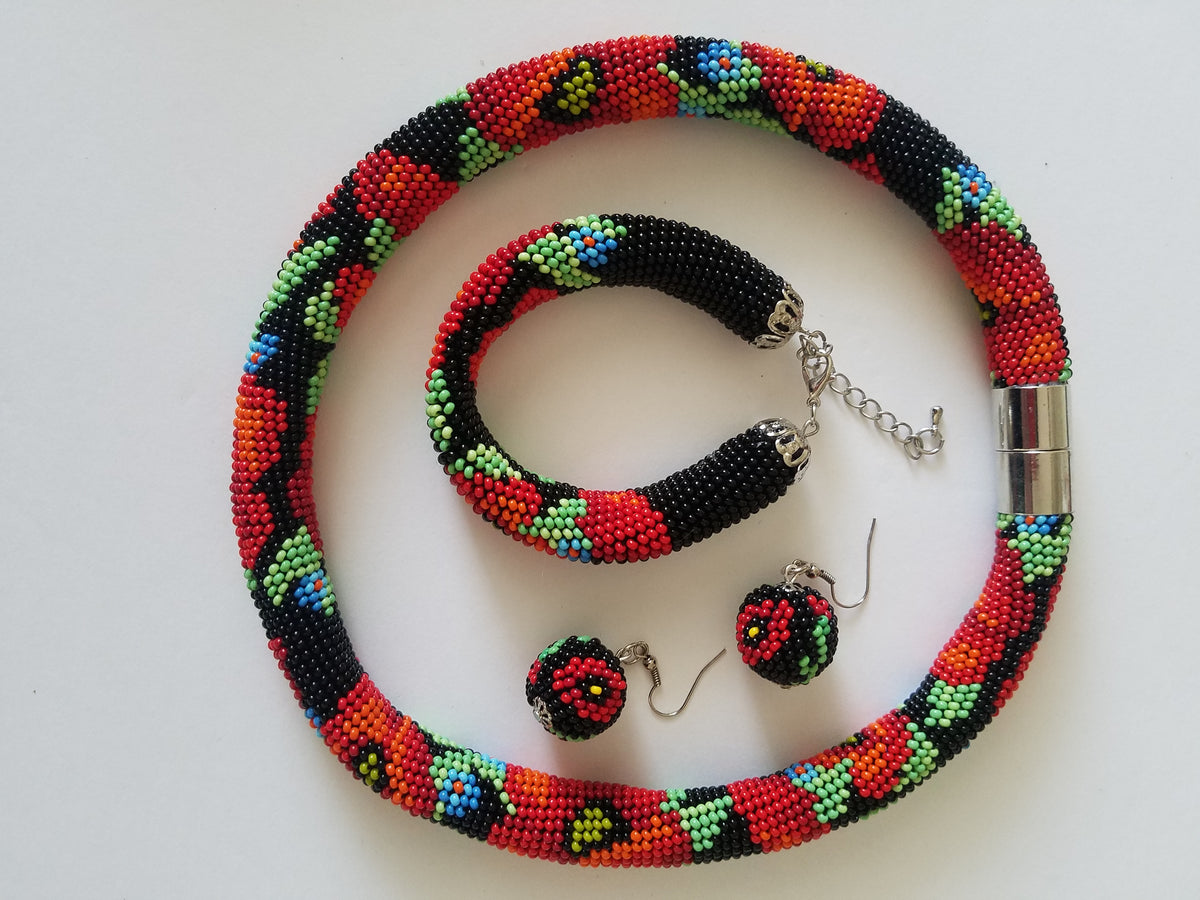 Flat lay of the black Poppies beaded choker, bracelet and beaded ball earrings with silver clasps