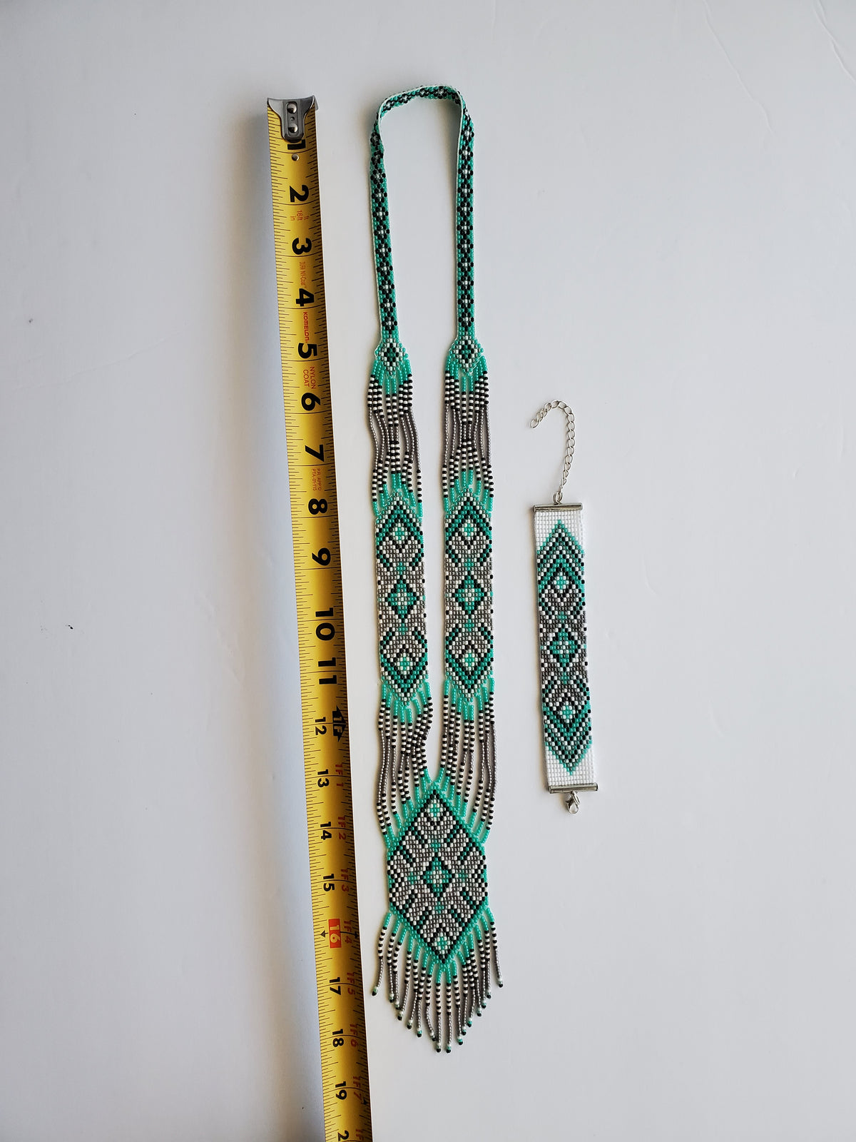 Mint green and gray loomed gerdan necklace with matching beaded bracelet next to a tape measure for scale
