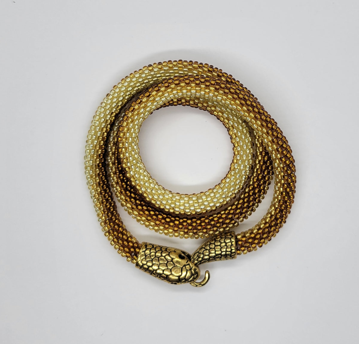 Golden amber ombre beaded snake necklace coiled in a spiral, antique gold scaled head, flat lay