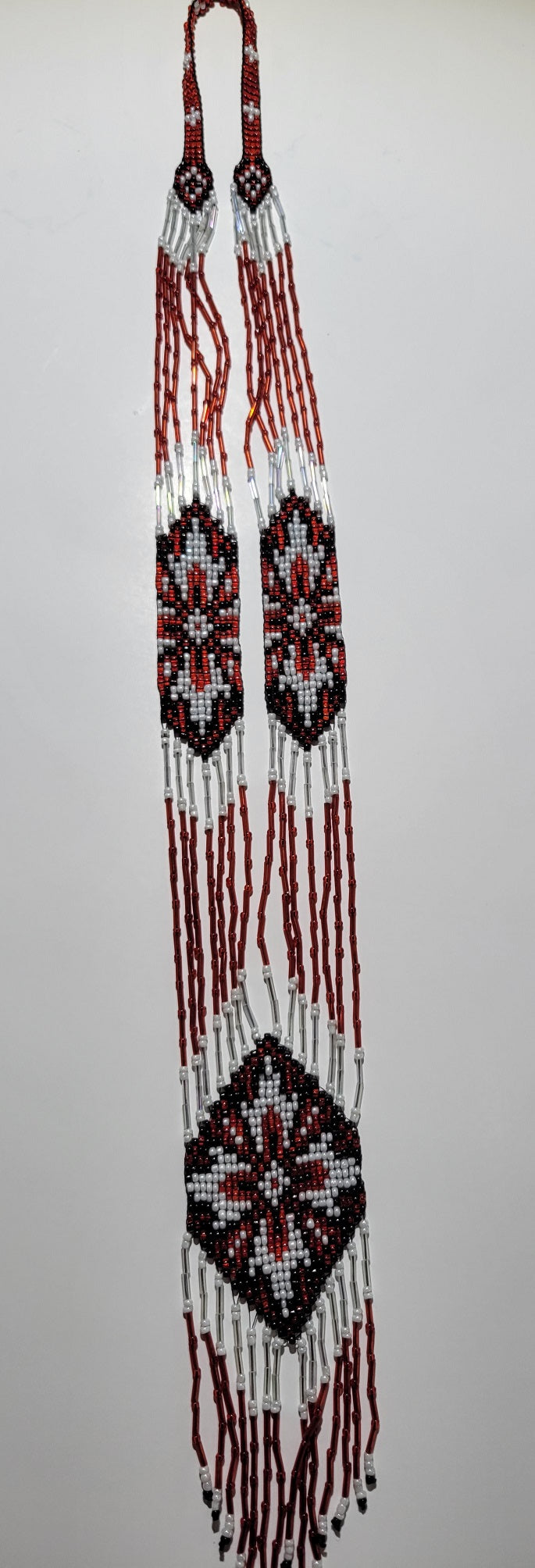 Handmade gerdan necklace in red, white and black glass seed beads with snowflake medallions, flat lay