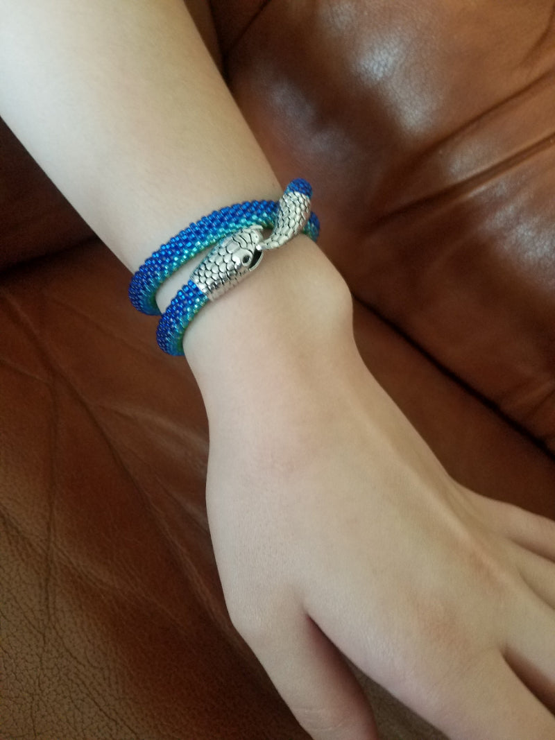 Blue and turquoise beaded snake bracelet wrapped twice around the wrist, silver snake head clasp