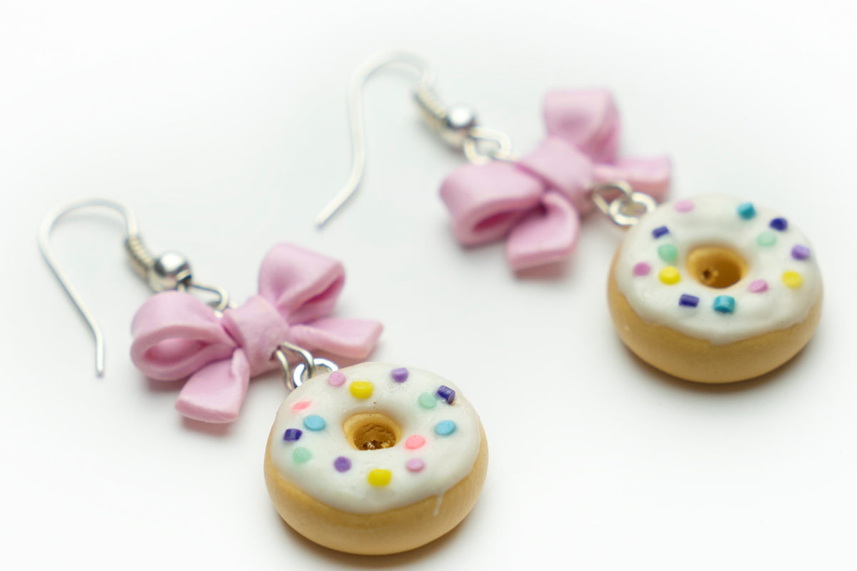 Handmade polymer clay donut earrings, angled close-up of sprinkle frosted donuts and pastel pink bows
