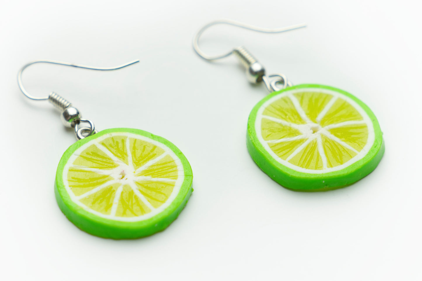 Handmade polymer clay lime slice dangle earrings, angled close-up showing the fruit detail