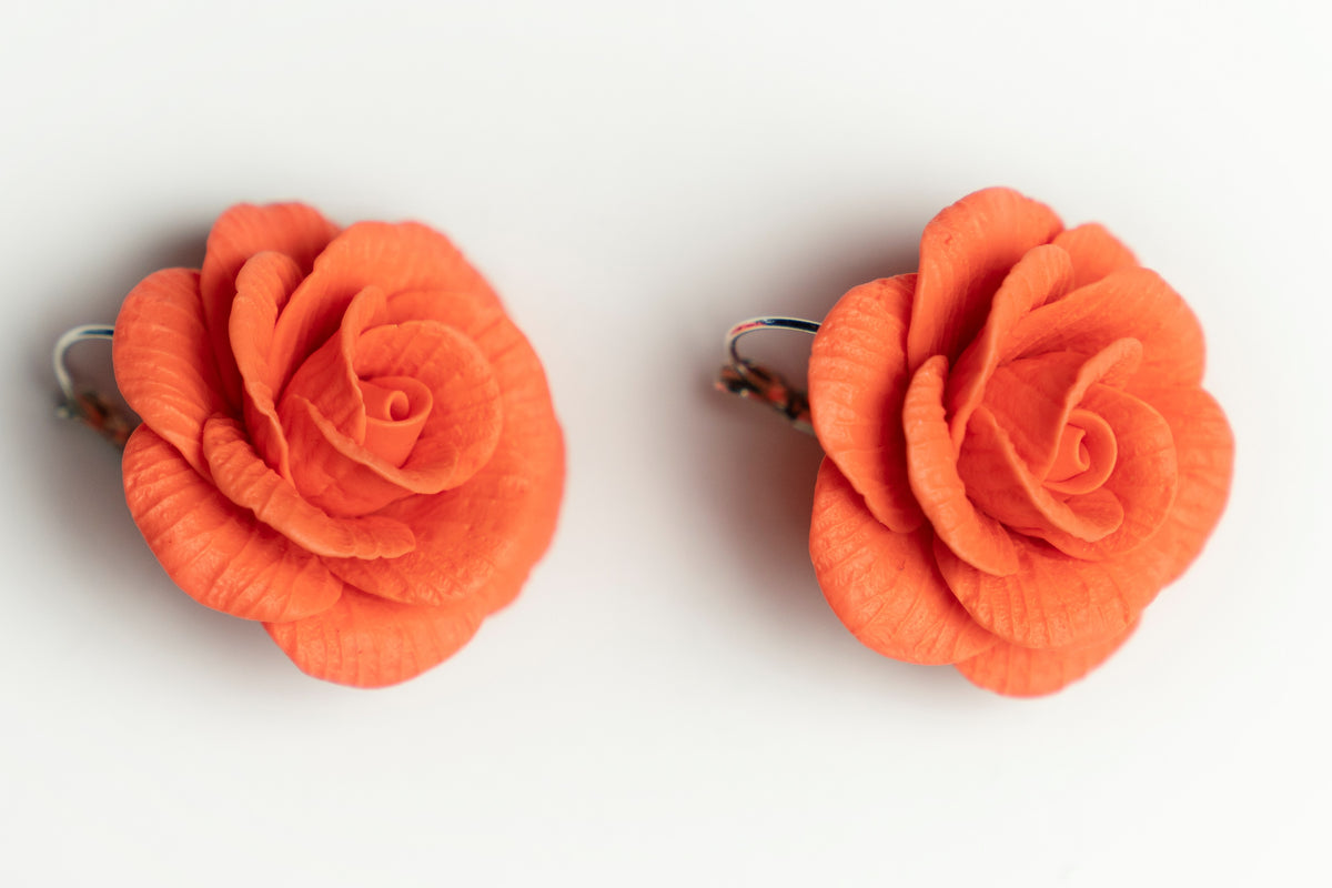 Top view of big red rose polymer clay earrings with silver lever-back ear wires