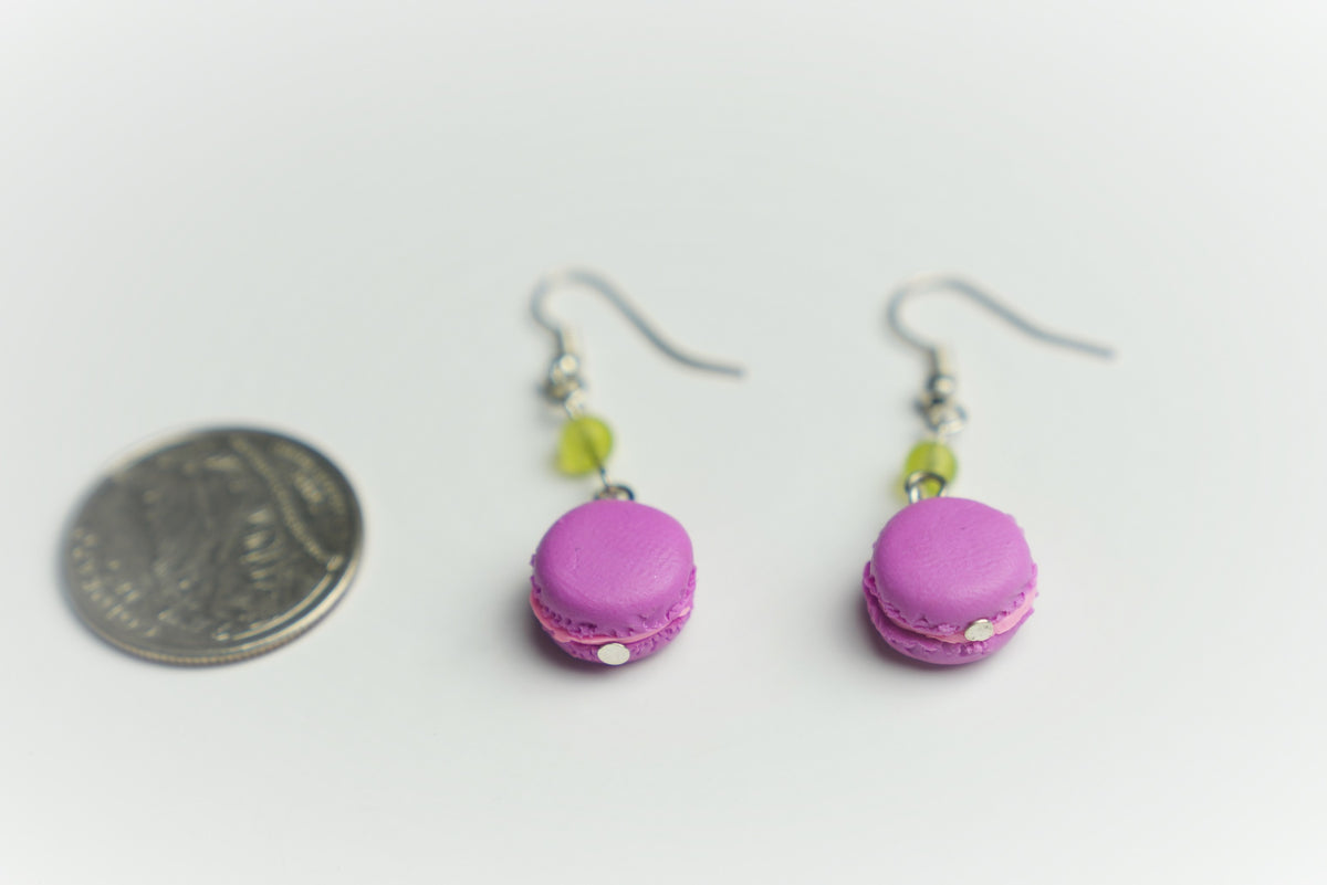 Pink polymer clay macaron dangle earrings photographed next to a coin for size comparison
