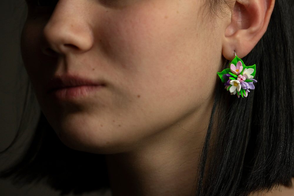 Spring Flower polymer clay earring worn on a model's ear, floral cluster with bright green leaves