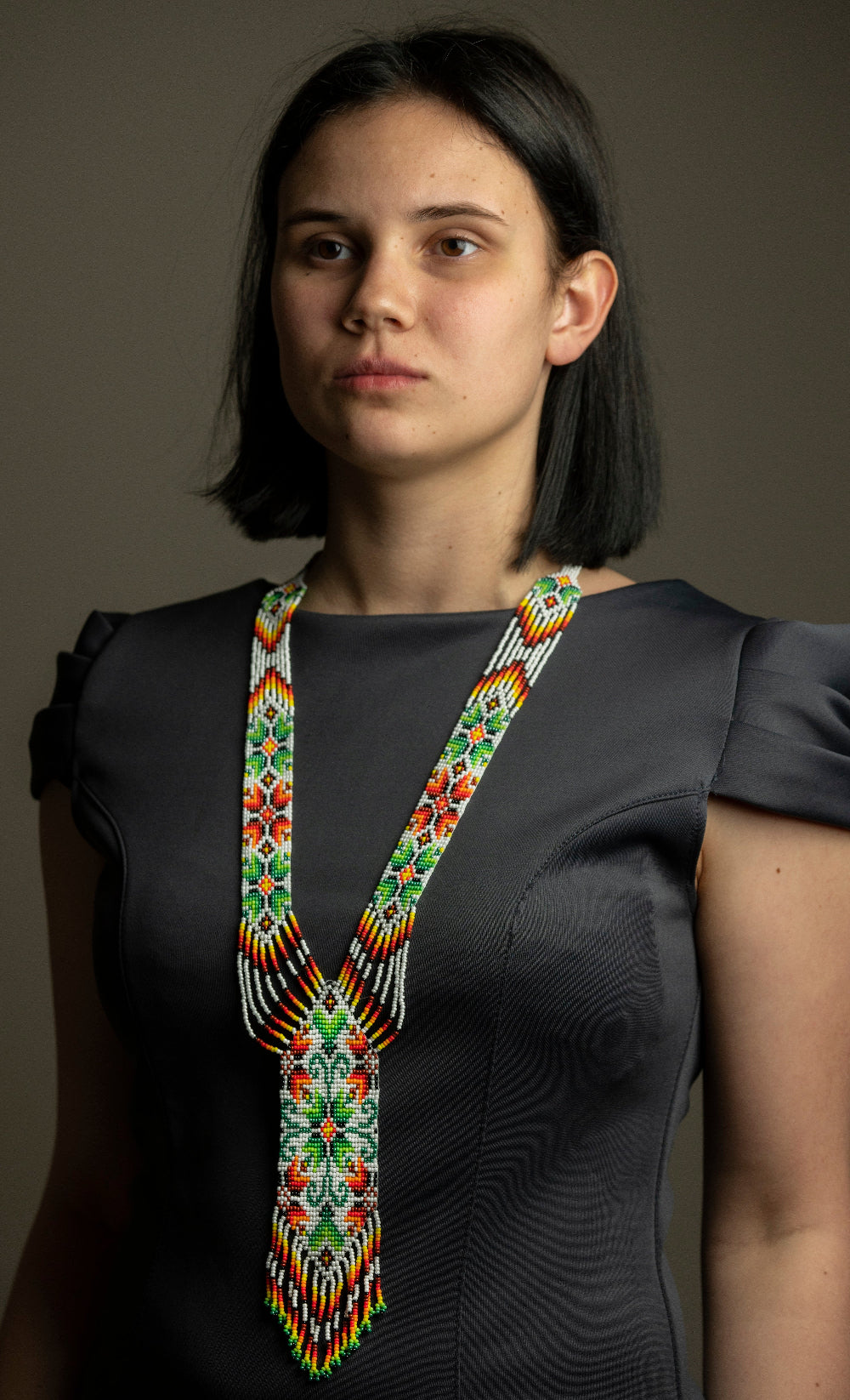 Beaded gerdan necklace "Gerdan" in white, green and red floral pattern worn by a model in a gray dress