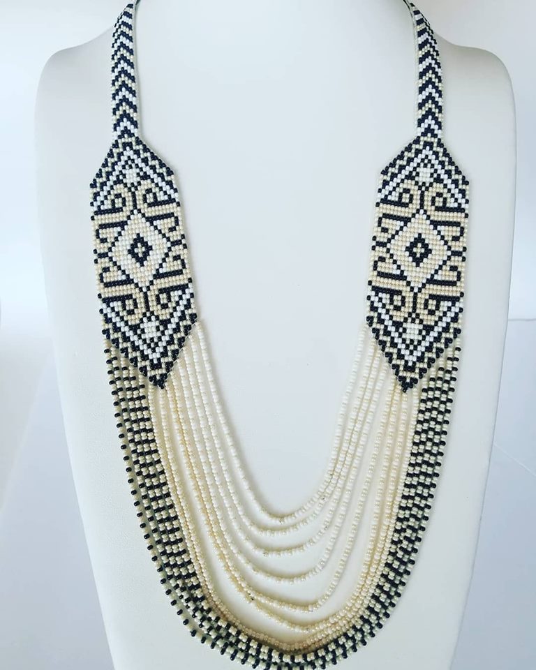 Handmade beaded gerdan necklace in cream, white and black folk pattern with draped strands on a bust
