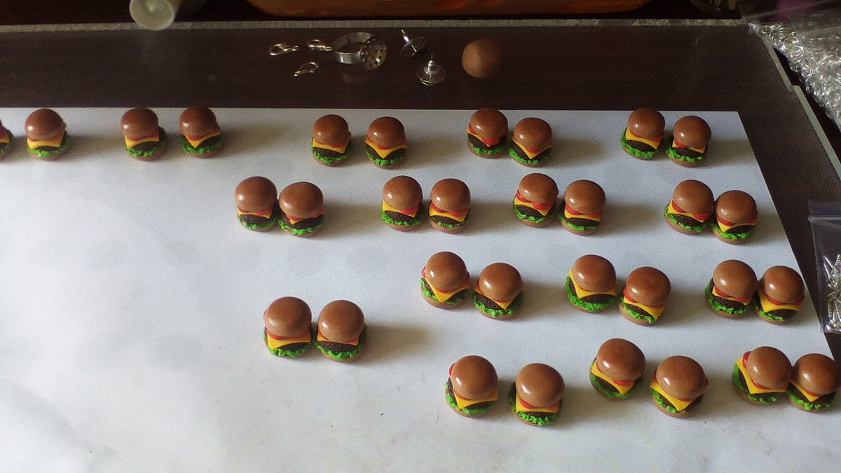 Rows of miniature polymer clay burger charms on the work table before becoming Hamburger earrings