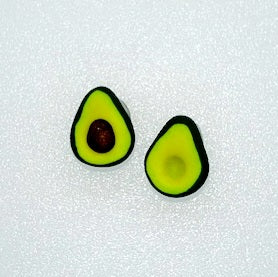 Close-up of two miniature polymer clay avocado halves, one with a brown pit, on a white background