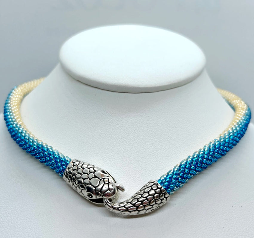 Handmade snake choker in ocean blue and cream ombre seed beads on a display bust, silver head clasp