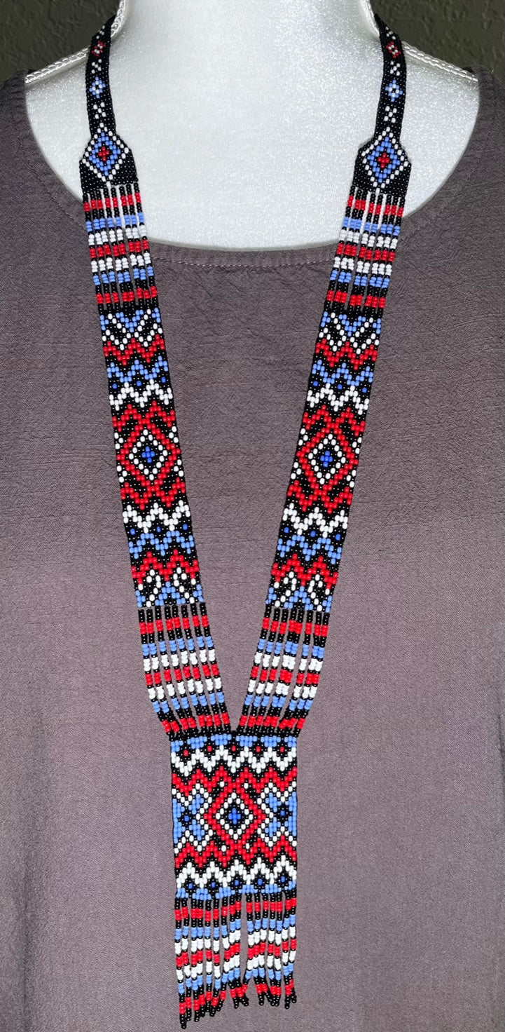 Loomed gerdan necklace in red, blue, white and black zigzag pattern with central diamond panel and fringe
