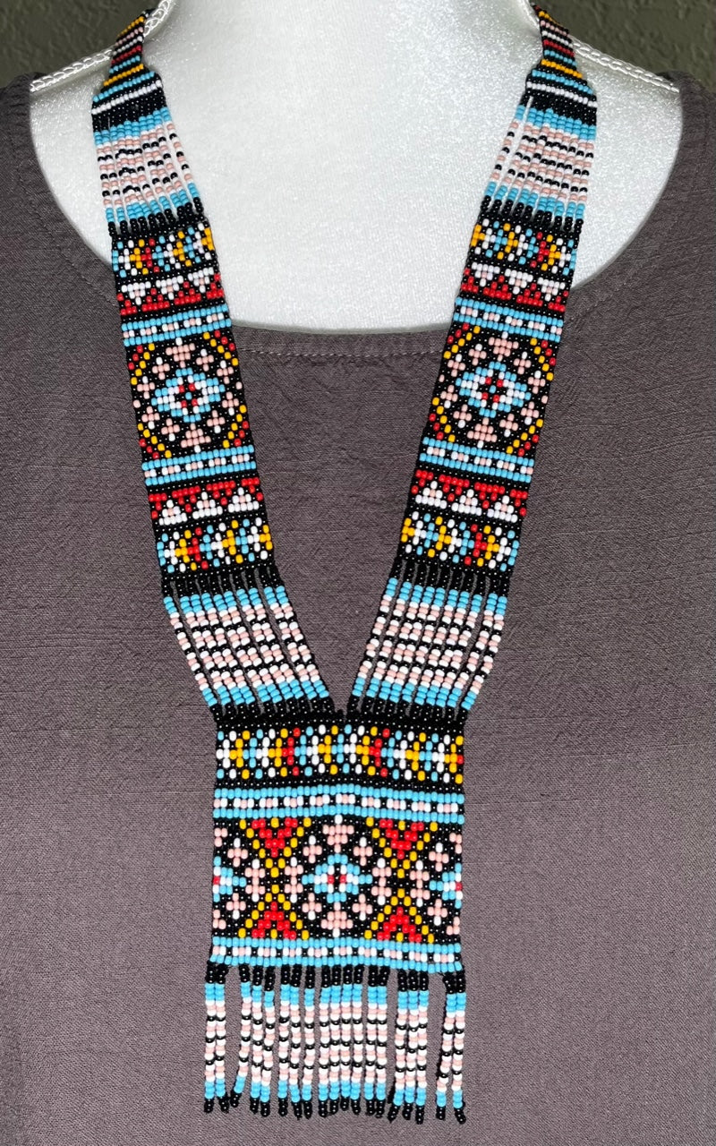 Multicolor beaded gerdan necklace in sky blue, pink, red and yellow ornament worn on a gray-draped mannequin