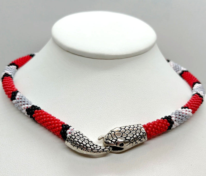 Handmade beaded snake choker in coral red, white and gray on a white display bust, silver snake head clasp