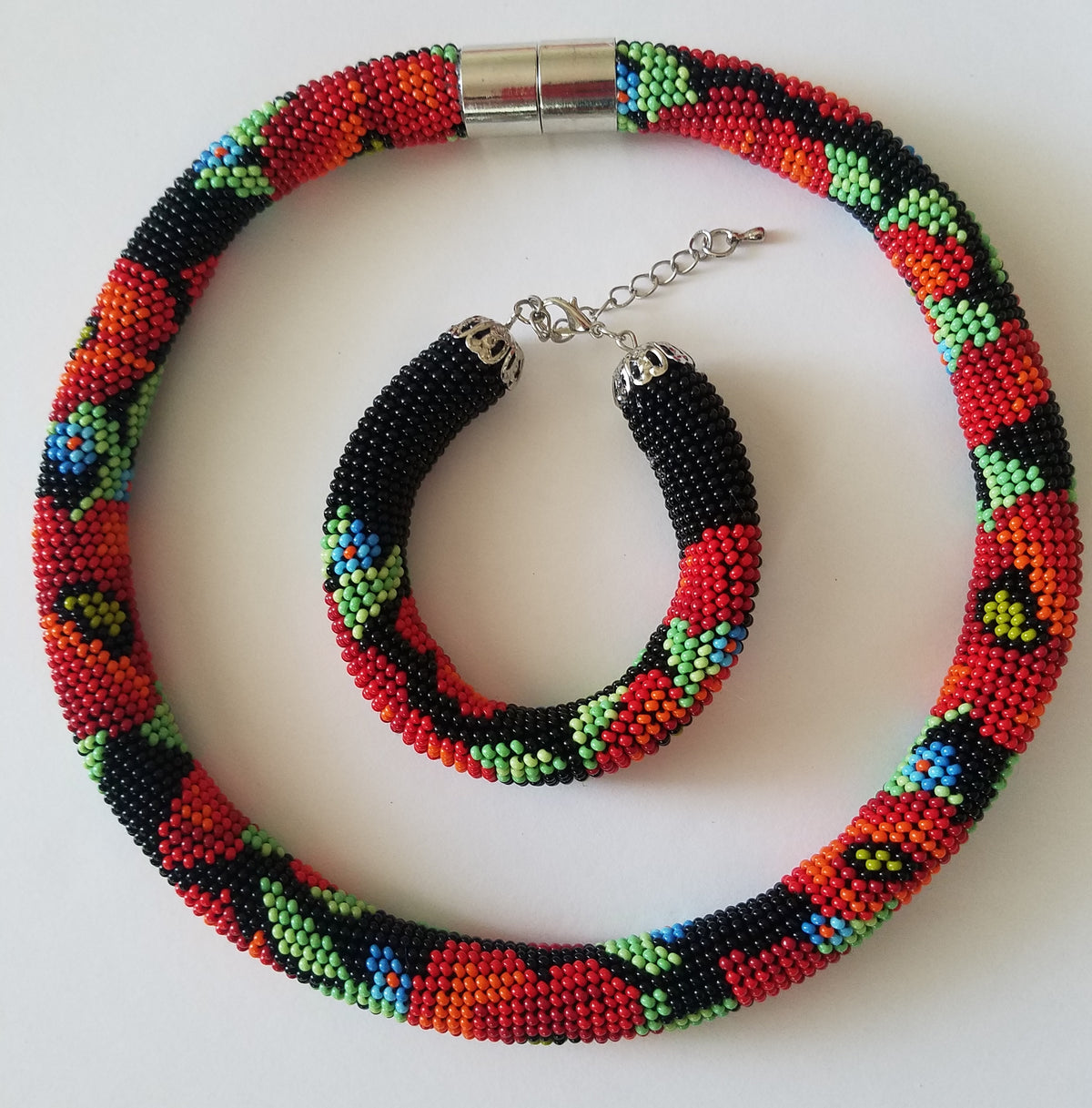 Beaded Poppies choker coiled around its matching bracelet, black colorway with extender chain