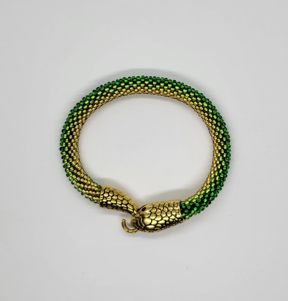 Handmade snake bracelet of green and gold glass seed beads coiled with an antique gold serpent head clasp