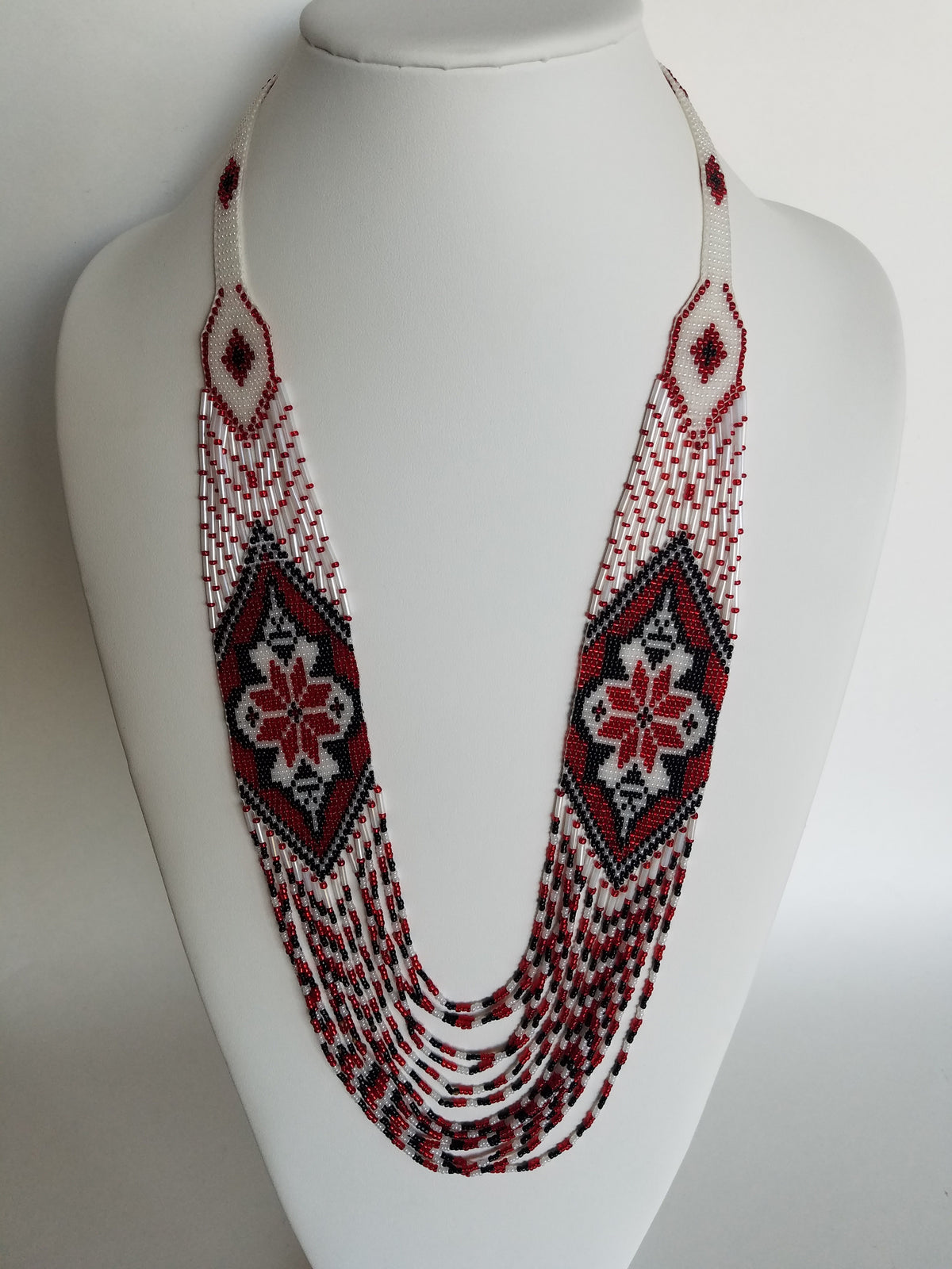 White bead crochet necklace "Marichka" accented with red and black zigzag beadwork, displayed on a bust