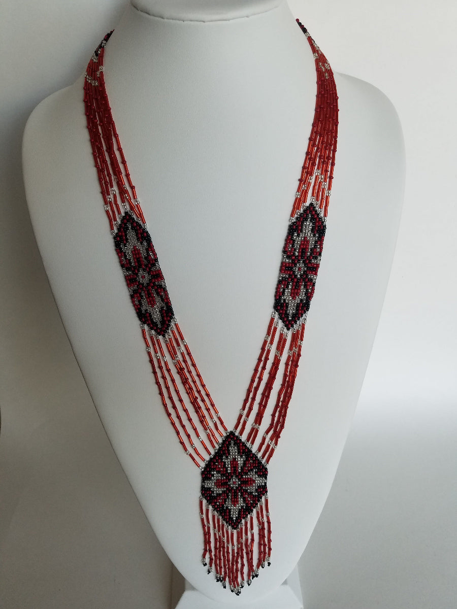 Red, silver and black beaded gerdan necklace with star motif medallions on a white jewelry bust