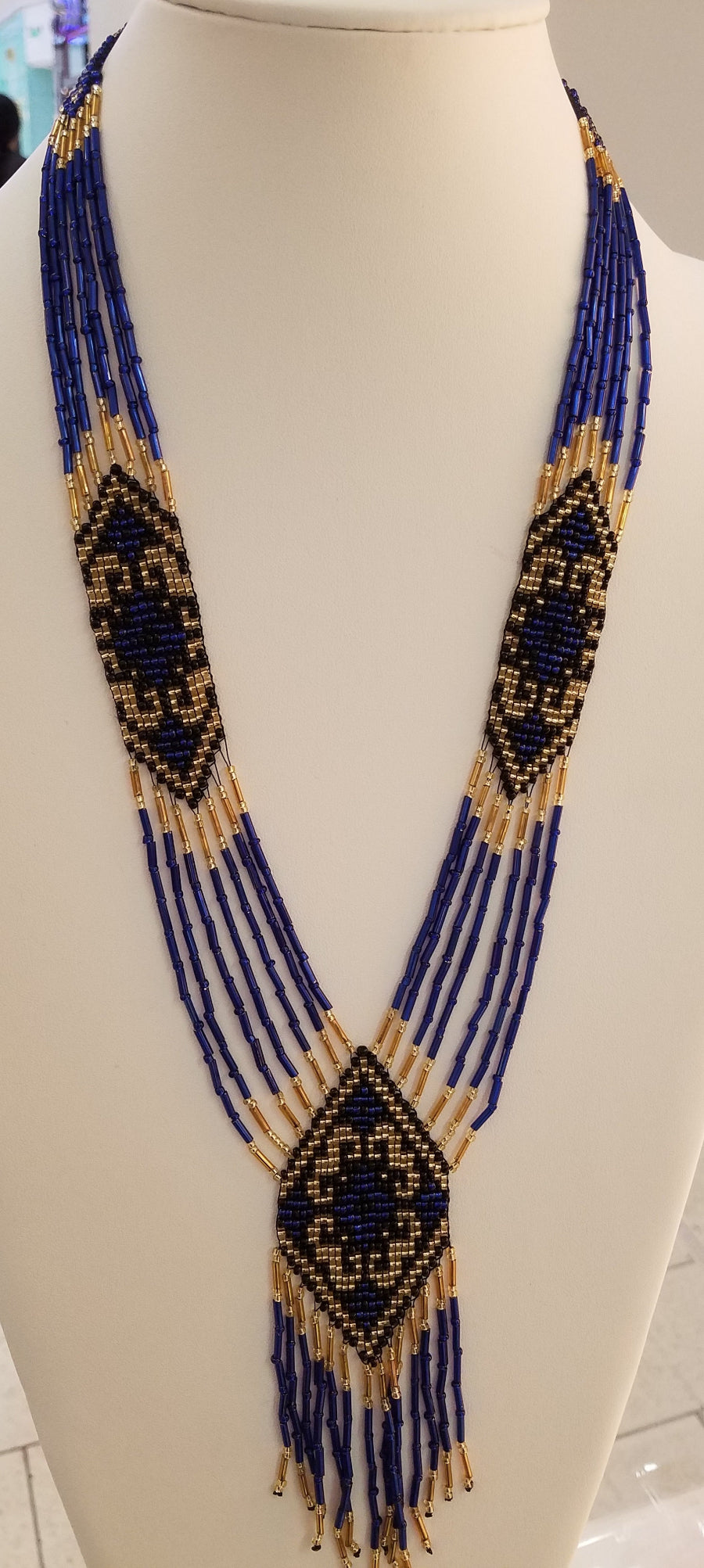 Loomed gerdan necklace in royal blue and gold glass beads with ornamental diamond panels, shown on a display bust