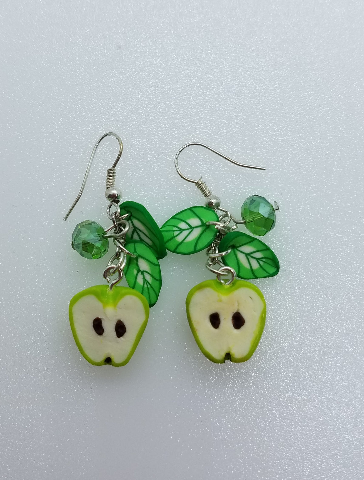 Handmade polymer clay earrings with matching green apple halves, leaf charms and crystals on silver hooks