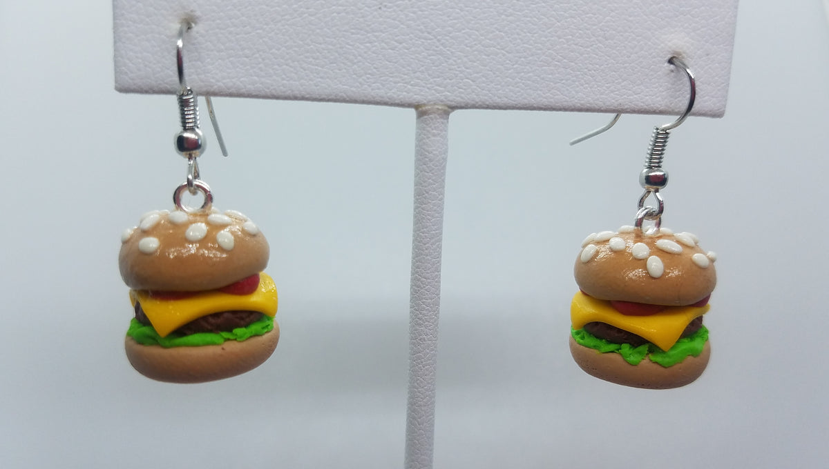 Handmade cheeseburger earrings in polymer clay hanging from a white earring display stand