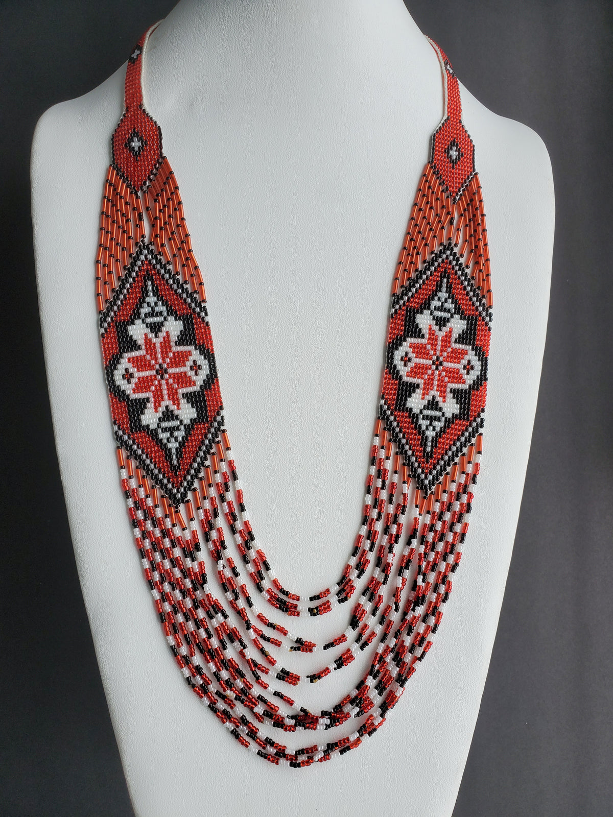 Red, white and black "Marichka" seed bead necklace shown from the front on a jewelry display bust