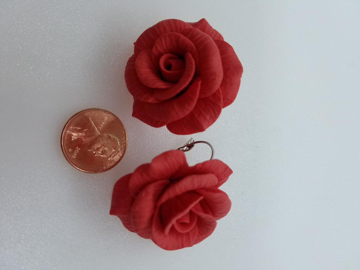 Handmade red rose polymer clay earrings with a penny for size comparison on black