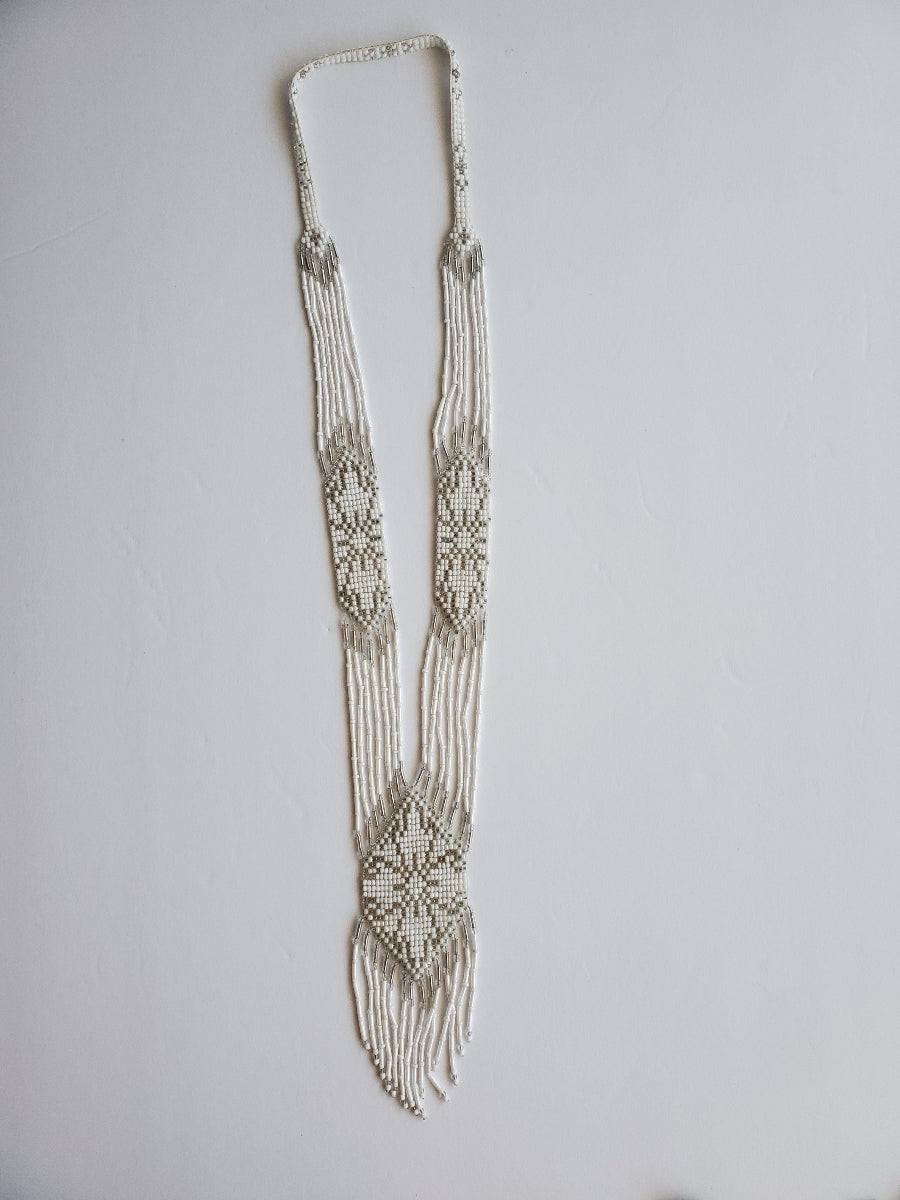 All-white loomed gerdan necklace with subtle silver accents and long beaded fringe, flat lay